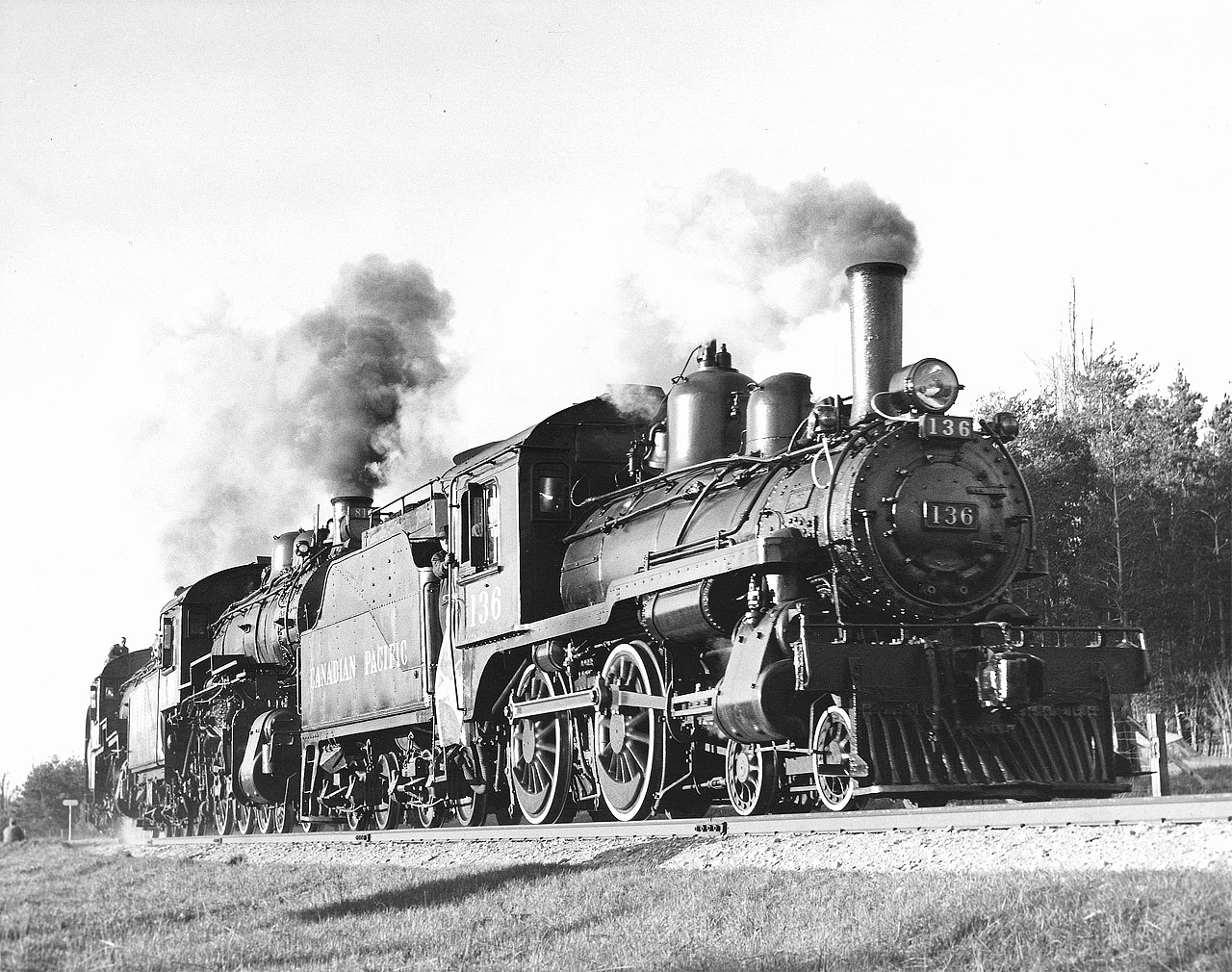 Looking out from the gangway is L. L. O’Brien Master Mechanic London Division a dour looking Official.  The Bruce branches were under the jurisdiction of London Division at the time but were later restored to their traditional Bruce Division.  Also in the cab besides engineer Charlie Waters and fireman Peter Fairfull was Nels Perkins General Locomotive Foreman Lambton and Dow Alexander Air Brake Instructor. The ancient A1 air brake was what brought him up from the Falls (Smiths Falls).  Five men in a tiny cab and only three seats!   
This close up look as the engines round a sharp curve shows the simplicity of engine 136 a small 4-4-0 built in 1883 by Rogers Locomotive in Paterson New Jersey.  Heavily rebuilt in Angus Shops in 1914 with a superheated boiler and piston valves it had little original content and was in fact newer than the two D10’s built in 1908 and 1912! It retained the Stephenson valve gear still in use on about 5% of the roster in the 1950’s.  It definitely did not have any “mod cons” with its Daylight injector, chain operated manual firebox door,  “Johnson” bar manual reverser, A1 air brake.  A hidden feature is a damper! Never heard of such a thing.  Word was sent from the regular man in New Brunswick about this however, it is not known if it was ever passed along to the engine crew.  Its original wooden cab was long ago replaced by a steel one off a U3 class 0-6-0 switcher adding to its ungainly appearance along with the high steam dome.  One good feature is its melodic whistle, much nicer than the standard CPR whistle which is a little harsh.  If you have heard it you will know what I mean.  Listen to it on Sentimental Journey “The Last Run” the first Canadian made LP record of railway sounds.  A very few original unopened copies are still available!   

 Raymond L. Kennedy