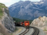 Winding around the bend in the shadow of the mountains, CN 5228 West splits the rock faces as it approches Jasper, Alberta at Mile 233 on the Edson Sub. GMD SD40 5228 is on the point with an unknown SD40-2W, and a rebuilt CN F7Aum still earning its keep (that is, a rebuilt F7 A-unit that was later converted into a B-unit with windows blanked off - they were the only F-units to receive the angular fuel tanks).