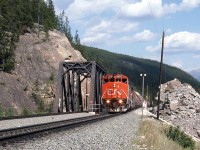 Rock faces, mountain ranges, trees and rail - Canadian railroading out west! CN SD50F 5434 and another SD lead a westbound train with a good-sized cut of colourful cylindrical hoppers on the head end, west of Jasper AB on the CN Albreda Sub. The bridges here are for the Miette River at Mile 7.8, just east of the Geikie mileboard.