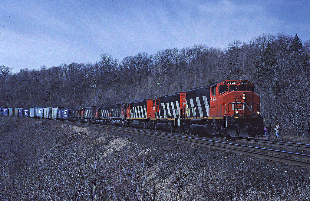 CN GP40-2W 9526 leads a mixed bag of MLW and GMD downgrade past the site of Dundas station with train #410 with a number of auto parts cars on the head end.