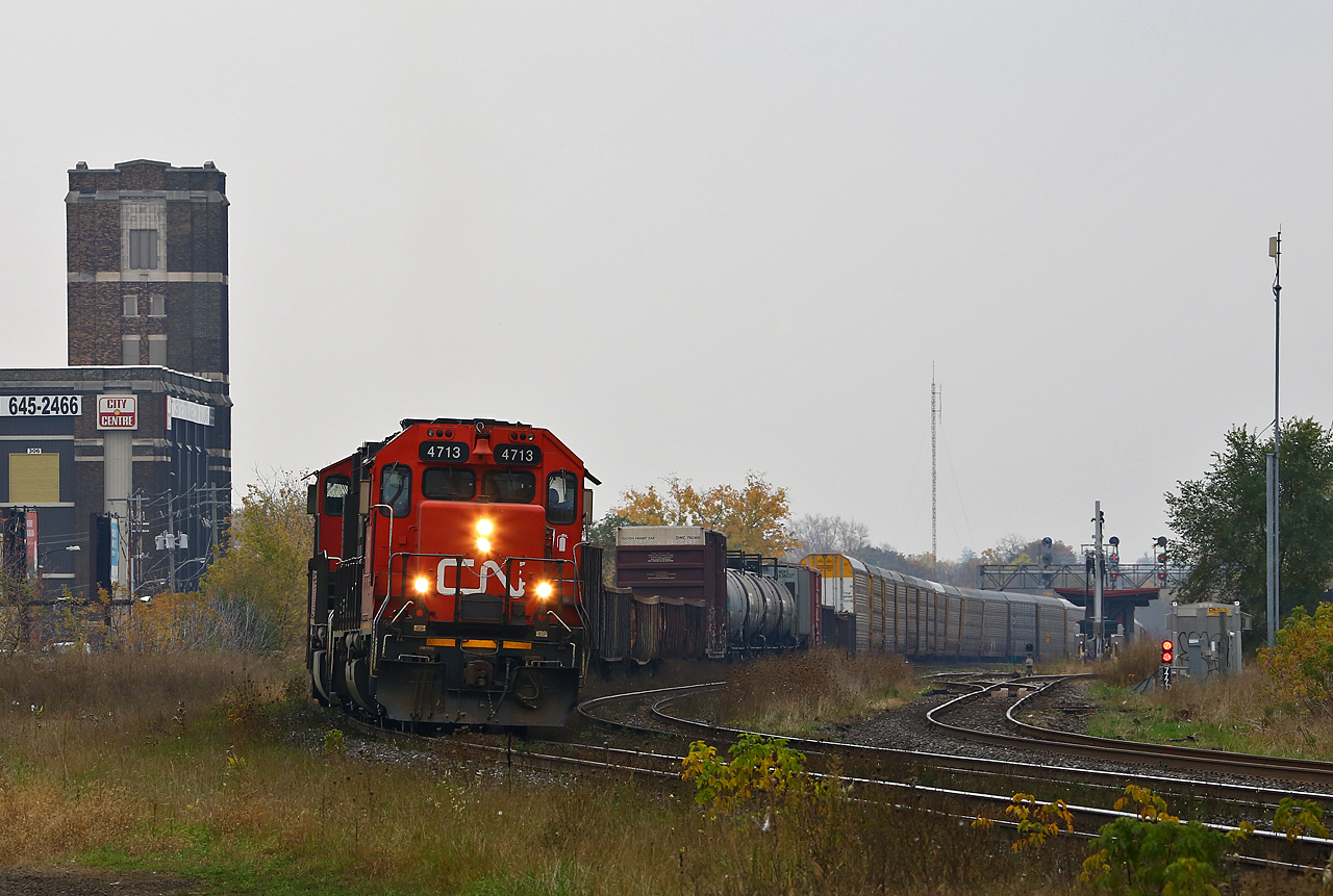 In an area that once was blanketed with the tracks of not one but two railroads, CN 438 passes the one remaining steam-era landmark in west London. Originally the Holeproof Hosiery company, the brown brick building in the background somehow has escaped the wrecking ball to become a storage facility. CN 4713 leads 5761 slowly pulls past the VIA depot in London with an unusually long train. They are running immediately behind CN 509, and both trains were running abnormally late.