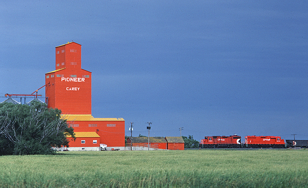 CP Rail GP38-2 3056 leads train #560 past the Pioneer elevator at Carey, enroute from Winnipeg to the US border at Emerson where CP (and CN) interchange with Burlington Northern and Soo Line.