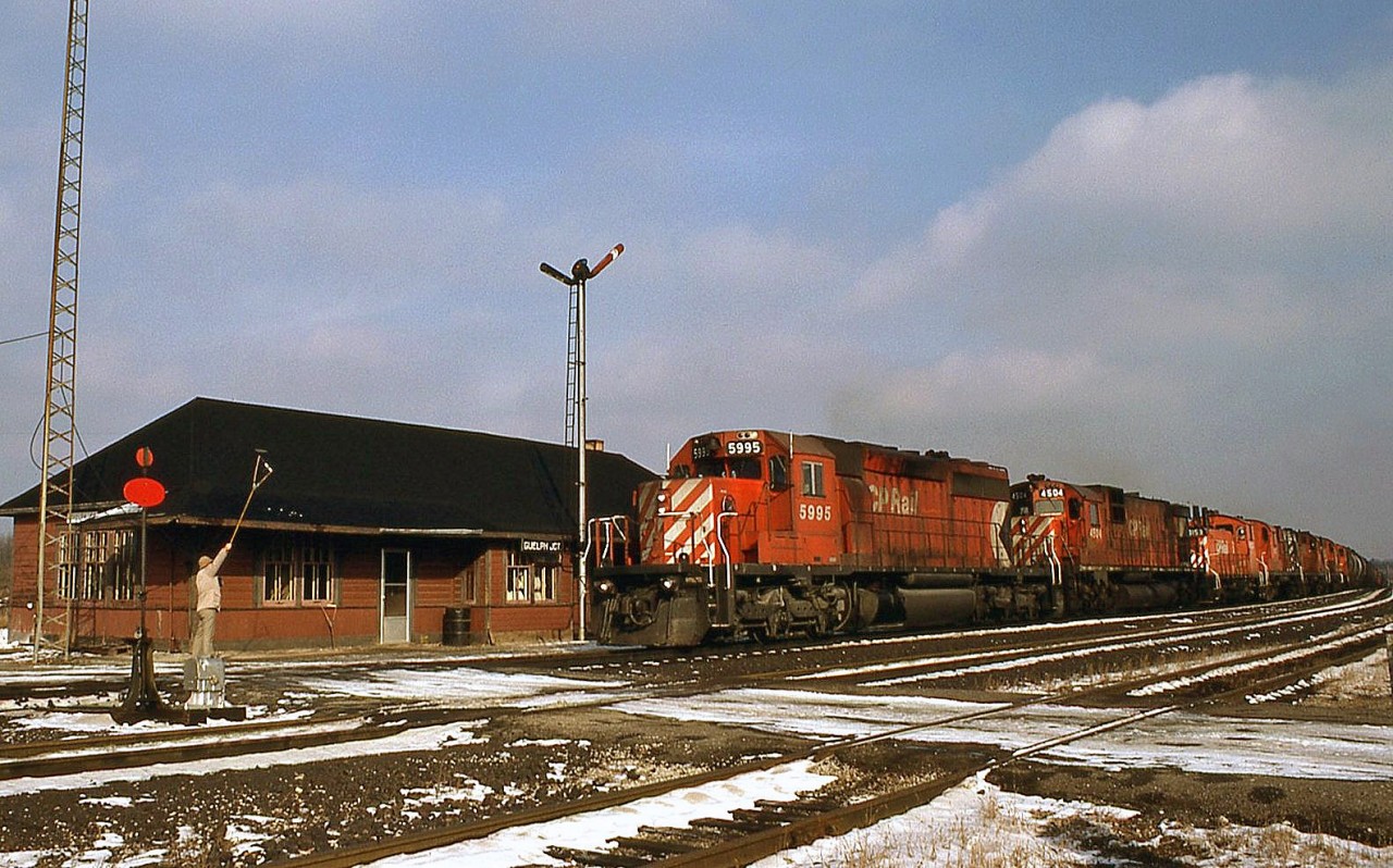 CP 5995 on the westbound "Pick Up" rolls into Guelph Junction, with the station attendant at the ready with orders to be hooped up to the westbound. Trailing SD40-2 5995 are C630M 4504, SW1200RS 8153(?), and four units that would be set off here at the junction (most appear to be RS18 roadswitchers).