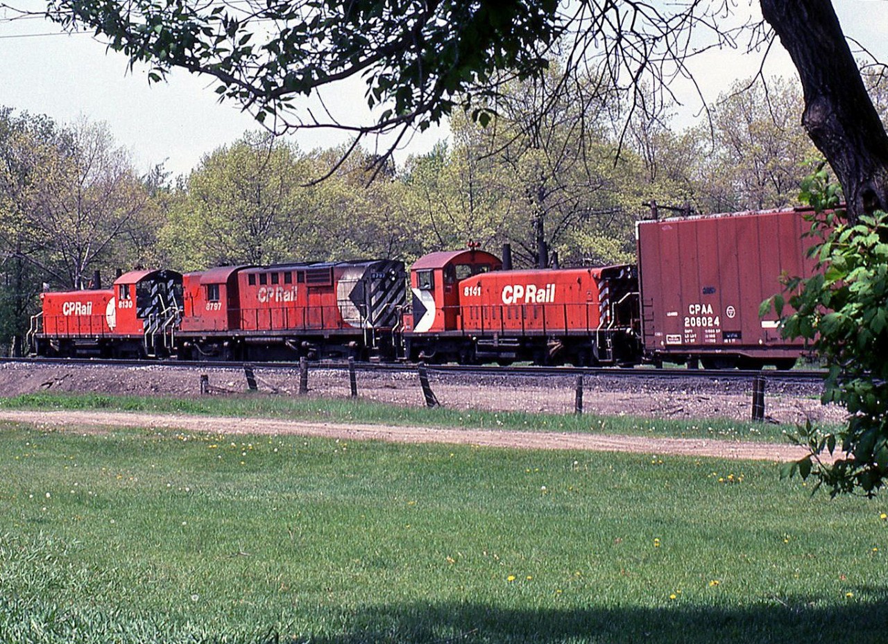 RS18 sandwich: white extra flags waving, little CP SW1200RS units 8130 and 8141 bracket RS18 roadswitcher 8797 on a westbound freight by Lambton Park, on the Galt Sub between the Scarlett Road and Humber mileboards.