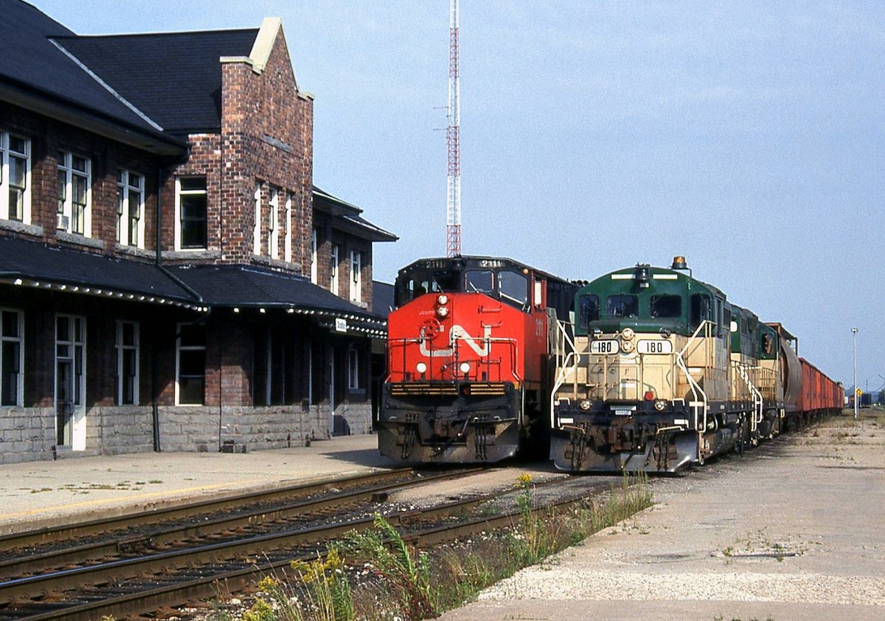 CN train 411 (MacMillan Yard to Sarnia via the Guelph Sub) passes by the station at Stratford with Bombardier HR616 2111 in the lead. On the track next to it sits a train of ballast cars with two Goderich-Exeter GP9's, 180 "Falstaff" and a 17x sister, which came from another operation of owner RailTex (they were originally built for the Quebec Cartier Mining railway).  The Goderich Exeter Railway, or GEXR, was created a year earlier in 1992 to operate CN's Goderich Sub (Stratford to Goderich line). In 1998, the GEXR would take over the Guelph Sub from CN (who leased the line to them) and handle its daily operations, as well as those on associated spurs and branches. In September 2014, it was announced CN would sell part of the Guelph Sub to GO Transit parent Metrolinx, with CN (at this point, actually GEXR) retaining rights for freight operation on the line. But there are rumours CN might be taking back operations when the lease comes up for renewal in the near future.