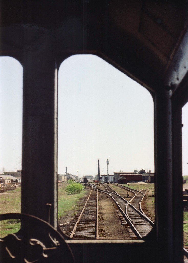 Here is a view of the old Rectory St locomotive shop area in what is now London East on the timetable. There is no trace of this facility left, I am told, save for the mainline. One can see a bit of what was a complete circular roundhouse;and a passenger/train order station. Rectory St is just behind the buildings in this eastward looking view, and there also was a watchman's tower at the road crossing. The photo is taken from the cab of the last in a string of old locomotives; a scrapline, of which I do recall featured #'s 1710 and 1709, but did not record the number of the unit I shot this image from. Perhaps it is an old MLW S-3?? Something like that.