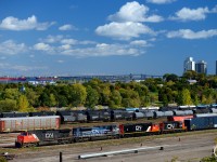 CN 422, with engines CN 2676, CN 8100, CN 5441, CN 7000 roll on the mainline of the Grimsby/Oakville "Hot Track" with the rest of Hamilton yard in the background. Two vessels are seen in Hamilton Harbour waiting for a port berth, <b>Heloise</b> and <b>Federal Elbe</b>. Heloise docked at Richardson's terminal near the QEW, and Federal Elbe  at Federal Marine Terminals dock in Hamilton. Photo notes: used a polarizer filter.