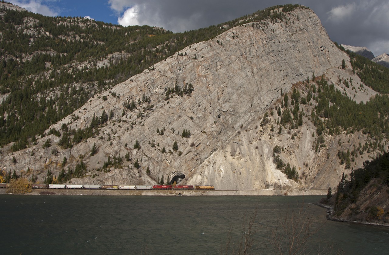 Eastbound grain empties with a UP AC4400CW on the point passes scenic Crowsnest Lake