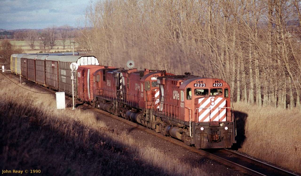Two MLW C-424s sandwich an M-636 at Mearns Road, Bowmanville, ON in late March 1993. The low angle winter afternoon sun lights up this westbound.