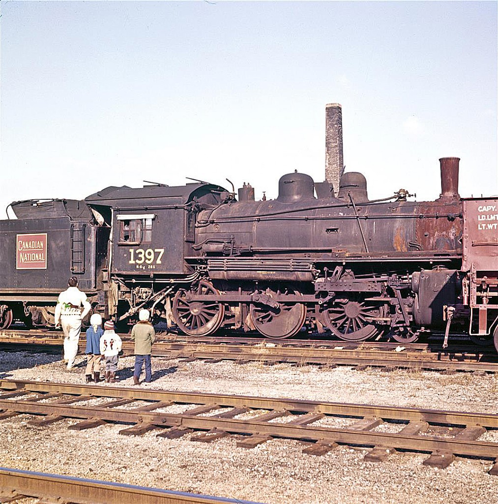 Mystery Solvers Needed!


For those that may not be aware of the story, over 35 years ago - through a strange twist of fate - I became the guardian of a small Canadian railway slide collection.  Until I restored and published the images in September, I did not know who the photographer was.  During those mystery years, I can’t tell you how many hours I studied this picture… hoping that perhaps it held the clue to the photographer’s identity.  Who was this man with the three small children?


Within hours of publishing the collection, the Canadian railfan community came together to identify the photographer as the late Del Rosamond, from Pembroke, Ontario.  With the help of social media and a very interested Pembroke historian / detective (thanks Dave!), I was able to connect with Del’s remaining family.  They have been very gracious and supportive – and have given me permission to migrate his collection to Railpictures.ca.


And what about those people in this photograph?  Turns out his family doesn’t know either.


I’d be grateful if anyone can identify this CNR boneyard.  The only clue (perhaps beside the locomotive itself) is the single brick chimney. Bonus points if someone can identify the people!


A few weeks ago, I added five new images to Del’s on-line photo gallery (80 images to date).  I hope you’ll visit at:   www.CanadianSteam.Smugmug.com