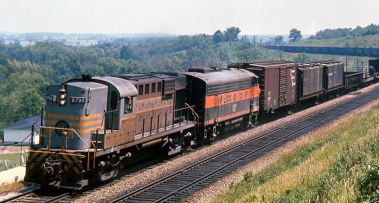 More 60's leased foreign power: CP RS18 8798 leads a 700-series Bessemer and Lake Erie F7A unit westbound through the curves of the Galt Sub at Mile 35, climbing up the Niagara Escarpment in Milton Heights near the present-day Kelso Conservation Area. Ballast or triple hoppers make up the majority of the train, behind a classic 40' stacked lettering boxcar, a pair of "slab side" covered hoppers, a gondola and two piggyback flats on the head end.

Along with the Union Pacific FA/FB's, the B&LE F7A's and F7B's were another group of power leased by power-short CP in the 60's.