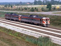 VIA train 181, running from Toronto ON to Buffalo NY, has just   passed under the Welland Canal (out of Welland, the Welland County Speedway is visible in the background). Power today is the   usual Budd RDC cars, a former CP Rail RDC-2 and RDC-3 still in   action red colours (possibly 9115 and 9021), both maintained by CP   out of CP's John Street Roundhouse for VIA (as opposed to the   dozens of VIA RDC's maintained out of CN's Spadina Roundhouse). <br><br> This train, formerly a TH&B train run with CP equipment, continued   to run into the VIA era until its last run on April 26th 1981, a   day before Amtrak introduced the Maple Leaf. The Budds ran on the   CN Oakville Sub (CP running rights) from Toronto to Hamilton, TH&B   Welland Sub from Hamilton to Welland, and Conrail CASO Sub from Welland to Buffalo, using CP Rail (Toronto to Kinnear), TH&B (Kinnear to Welland) and Conrail (Welland to Buffalo) crews for each leg of the journey.