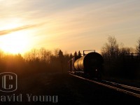 <b>Spring Sunrise.</b> As the days get longer the better your chances were of catching the daily freight ex Fort Frances to Thunder Bay arrive into the Lakehead. We are about 40 minutes into the daylight hours as CN A436's tailend passes by me at mileage 15, approaching B/E OCS limits at Evans as the sun peaks above the still stark trees. Another month will pass before any leaves are seen on the trees the Thunder Bay region.