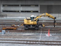 Today, I decided the visit a famous attraction in Toronto, the Ripley's Aquarium. While crossing the SkyWalk on the way there, I saw that down the tracks this particular machine was working on the tracks in the distance. After visiting the aquarium, I stopped at this spot right behind it for a while and heard a few blasts of a odd sounding air horn. Minutes later, I see this thing speeding down the tracks and I decided to try a pan shot as this machine will just fit in the camera frame, and it was going fast enough for a good one. Thankfully I didn't screw up, and I think it turned out fine. The machine likely belongs to the Toronto Terminals Railway which owns the tracks around Toronto's Union Station which is just to the right of where this image was taken. I believe it used for replacing ties. I've seen one of these before also being transported on the Canadian National Newmarket Subdivision in Huntsville, ON.