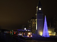 Lets just say, I was a bit high off the ground, and it was necessary to watch my step. An injured elbow was further harmed in the making of this photo. Here, the Canadian version of the Holiday train zips past the old North Toronto-Summerhill CPR station, with the now 9 year old Christmas tree adding to the scene. Hoping it would perform its slow rollby past Summerhill as it had done many years past, this year it zipped by at a good clip. Realizing a higher shutter speed would be detrimental to the lighting of the photo, I kept my shutter low sacrificing a slightly blurred leader. Having taken multiple low exposures beforehand, I thought adding a ghost effect would help compensate for the blur as well as add some Christmas magic. The Holiday train, introduced in 1999, has gone through a change of power three times. Starting out with SD9043MAC's and AC4400CW's, the AC4400CW took a primary role since until 2013. Being a loosely timed trip with a rather short train (for freight standards), newly rebuilt (ex GP9u's) GP20C-ECO's 2246 and 2249 have taken this year's role. Rolling by at 7:45PM, according to the clock tower, 01H would easily make it's next stop, Lambton yard by 8:15PM. As for the Christmas tree, it was first put up in 2005, probably for that year's Holiday train, which stopped at Summerhill that year. That was the one and only year it stopped at Summerhill, however the tree was still put up every year since. Slow rollby's, and happy horn blasts continued until recently. The importance of the location is not as recognized now, with this year's train passing at around 35mph, and the horn remained silent. Unless 02H will be doing this year's honours, but I think it's likely it'll rip through at track speed.