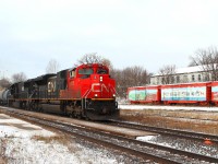 The sun is attempting to break through as CN 8921 and IC 1028 fight up the bank with a train consisting of loaded autoracks and mixed freight. The boxcar work of art is becoming very weathered after years of Canadian winters!