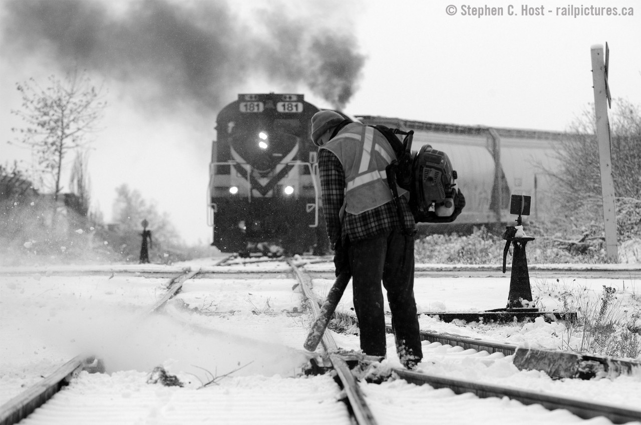 Winter's here - atypically early for this part of Southern Ontario - and snow fighting has already begun. A whoosh of snow is exiting the right of way thanks to a gas powered leaf blower operated by one of OSR's track maintainers, and a whoosh of MLW diesel exhaust exits OSRX 181 as Job 1 shoves cars up grade into PDI's new Massey Rd facility in Guelph.