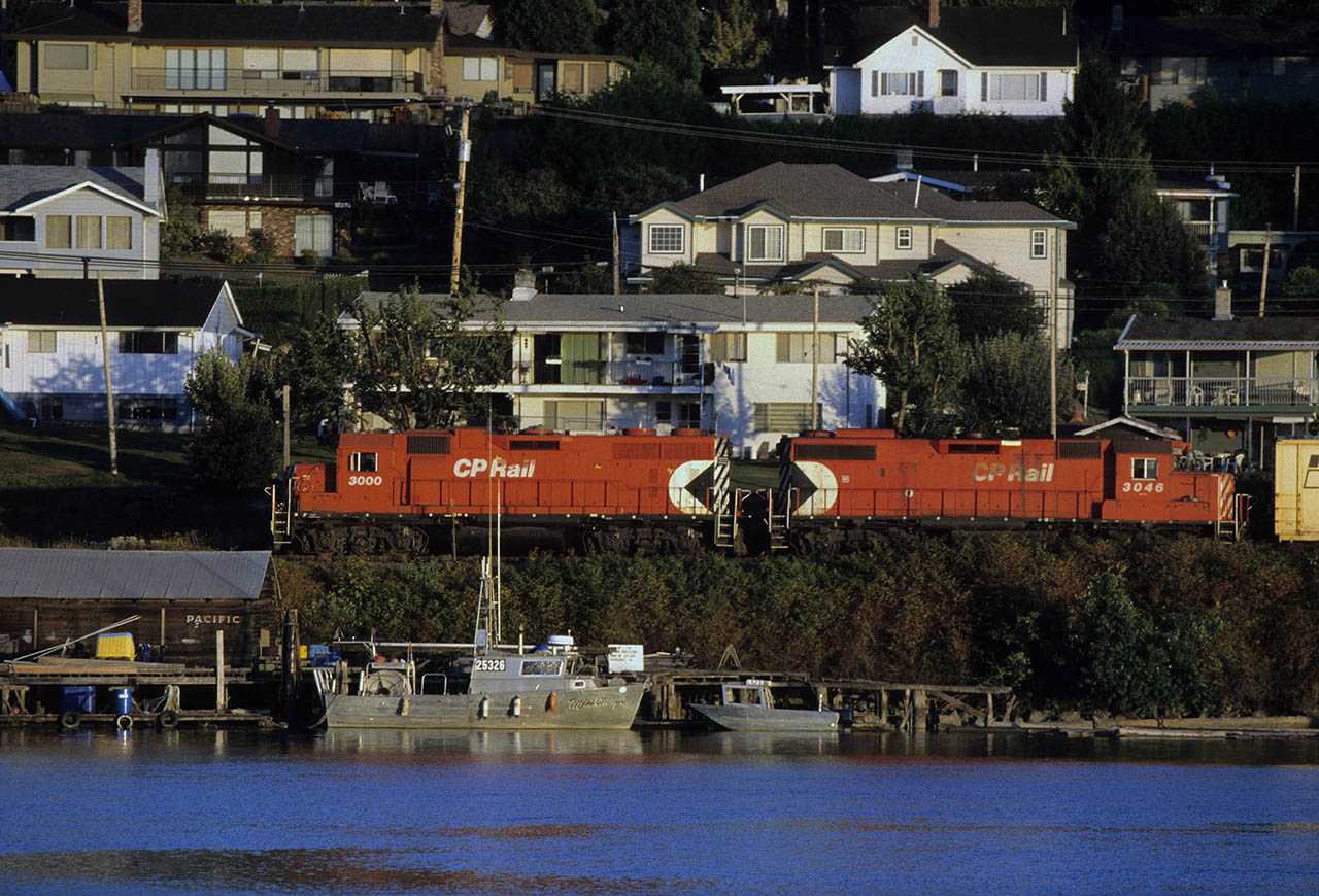 CP locomotive 3000 rolling past homes on the north side of Delta along the Fraser River east of the Alex Fraser Bridge by one city block.