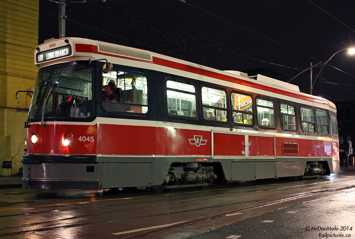 The TTC's fleet of 52 articulated ALRV streetcars rule the 501 Queen, but smaller CLRV's do show up from time to time - often in times of car shortages or changeoffs, whatever is left in running condition at the carhouse or yard gets send out. TTC CLRV 4045, bound for Long Branch, pauses near Queen and Victoria on a wet evening.

A gleam of what the photographer was doing this particular evening can be seen reflected in one of the windows, prior to his boarding of another 501 car not too long after pressing the shutter.