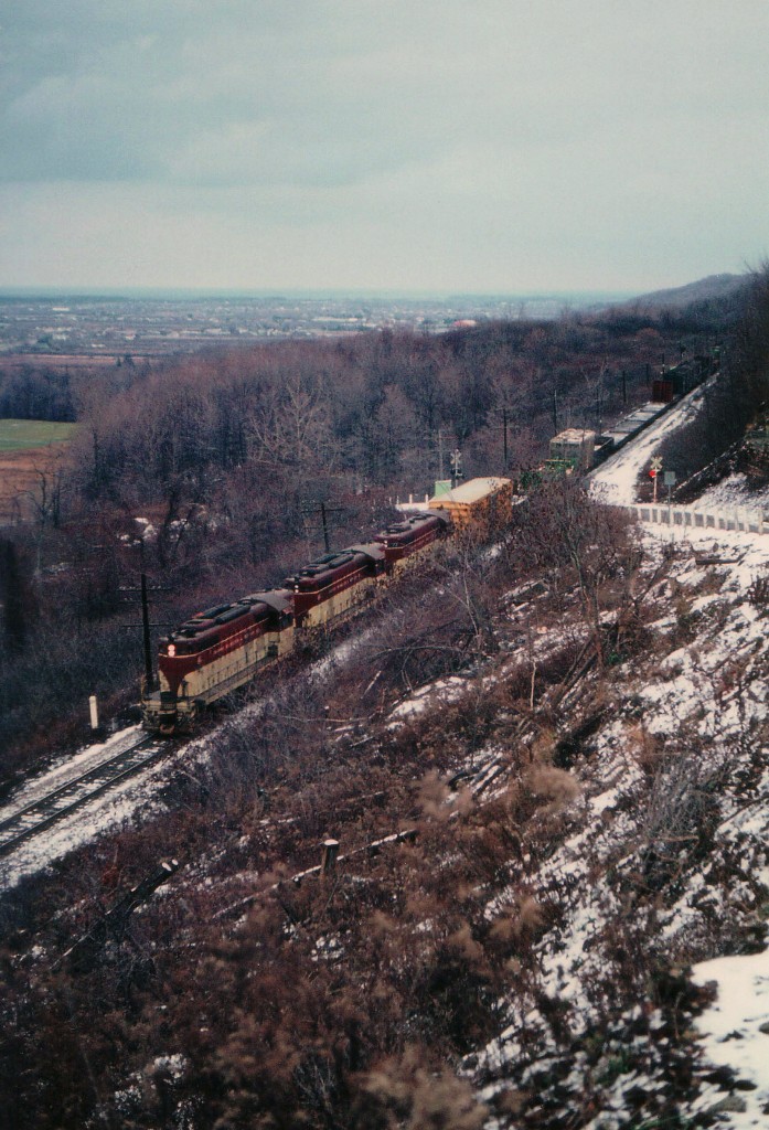 A miserable typical December day, but I finally, after many attempts was able to catch a train heading northward into Hamilton at the Dewitt Rd crossing in Stoney Creek. For some reason unknown to me the hillside was undergoing a brush-cutting, which provided a rare opportunity here. Followers of RP will notice how many photos of TH&B there are out there, but how FEW of them feature northward moves. Darn hard to catch. On this dark afternoon, TH&B 401, 402 and 77 is the power seen downbound. This area now is rather built up, huge homes crowded in a modern subdivision of the people kind, and still, Dewitt Rd is a steep climb, one way upward.