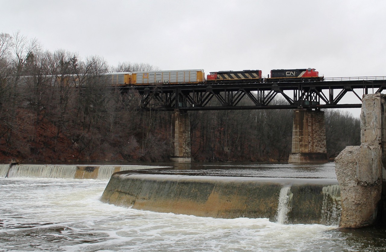 With a break from the earlier snow flurries CN 5291 and CN 5519 lead a mixed freight east across The Grand River viaduct at Paris. In the foreground is Penman's Dam.