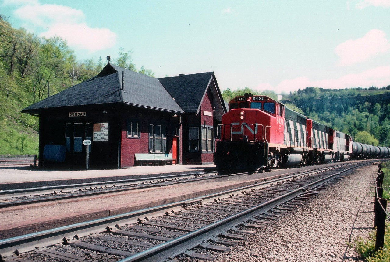 Back in the day when I shot this image, unfortunately I either had to know somebody or have an inside scoop on what was going on; because hand-held scanners were still relatively unknown (mostly just base units existed) and communication between railfans was sparse at best. So here I am on my own and this westbound comes roaring around the bend. Was it acid empties? Loads? Outside chance it was oil. I really don't know. At very irregular intervals I did see this train running either direction. About 40 tank cars and a caboose.  Perhaps someone out there can fill me in on the details of these trains.  Lead unit 9424 is the only number recorded. Ol' Dundas station still looks good, but it only lasted another 10 years or so before a stove fire lead to its eventual demise. Image looks to be taken around 1000 or so. Morning shadow.