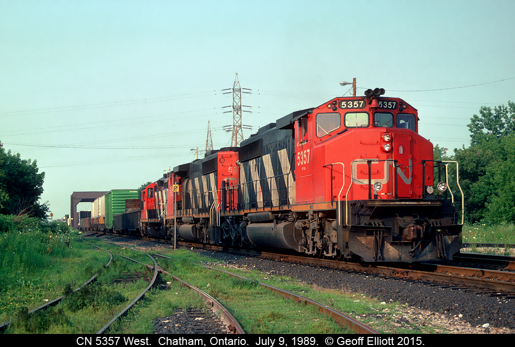 CN 5357 leads Windsor bound train #381 into Chatham on July 9, 1989.  The train will do a setoff and lift in Chatham, then back out of town to just east of the bridge in the background.  Once there, the Operator will line the crossover and the connecting track for 5357 to head south on the CSX Sarnia Subdivision to Fargo where they will swing west through the new connector and onto the CN CASO Subdivision to make their final run to Windsor.