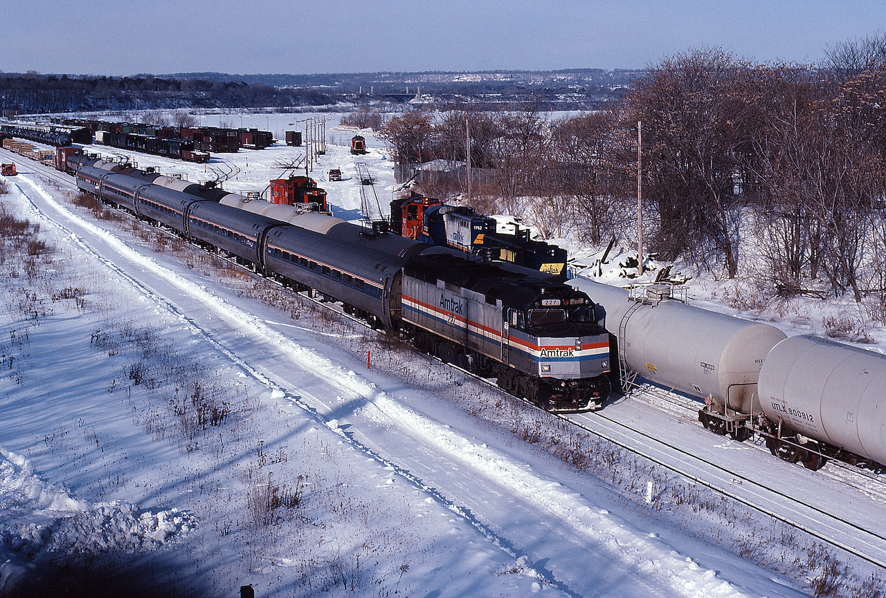 VIA 97 rolls down the hot track, passing the Railink yard jobs plying away in the yard.