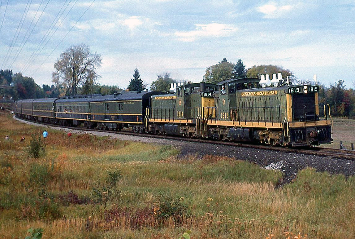 On September 28th 1963, the Upper Canada Railway Society (UCRS) ran an excursion to Lindsay with
Canadian National 4-8-4 steamer 6167, then the train carried on to Haliburton powered by a pair of GMD-1s. Seen here, CN 1915 and 1914 handle the train on a run-by near Kinmount ON, operating on CN's 55.5 mile long Haliburton Sub (Kinmount is listed in the timetable as Mile 33.4).

The GMD-1's were a special Canadian-only model built by General Motors Diesel Division of London ON for the CN starting in the late 50's (with a few built for NAR). Essentially an SW1200RS with a short hood, the 1900 series of 20 units were equipped with B-B Flexicoil trucks and steam generators to be used in commuter and local passenger service out of Toronto's Spadina Roundhouse and other points across the CN system (1900's were commonly used to switch passenger trains at Winnipeg's Union Station).

Note: geotagged location not exact.