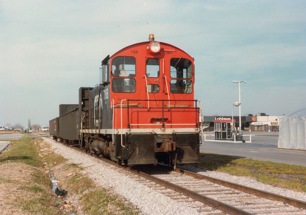 One of the difficulties with older photos is trying to pinpoint just exactly where the image was taken. In this case, for those who are familiar with St. Catharines; this shot would be just about right in the middle of the current Canadian Tire car-wash on Welland Av. There has been a lot of change in this area over the years. Gas pumps on the right part of the old Supertest/BP station that used to be there. And before that, it was a swamp.I still remember all the hassle of trying to anchor huge fuel tanks in swampwater surroundings. The tanks just did not want to stay down.:o) The Loblaw store in the background was demolished, there is a modern No-Frills just to the left currently. Apartment buildings and townhouses crowd the present day background. This local ran down to Port Weller Dry Docks as needed, sharing the Lakeshore Rd lift bridge with vehicular traffic back then. In this image, the local is returning to Merritton Yard, which is/was down by the CN Grimsby sub. This month is 20 year anniversary of when these former NS&T tracks were lifted. The SW-8 was retired in 1989.