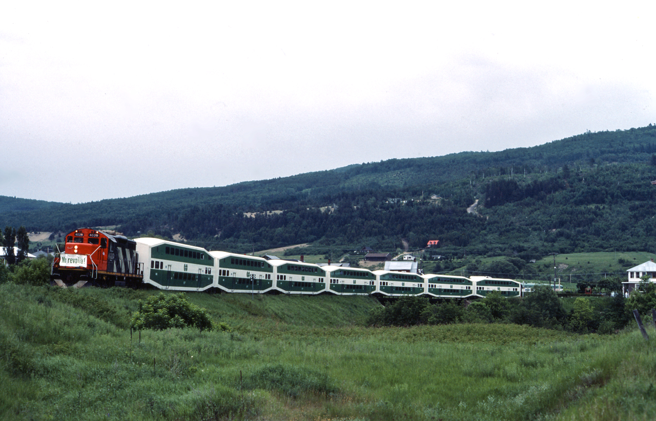 Le Tortillard Du Sainte Laurent excursion train rolls through Baie St-Paul, on the Murray Bay Subdivision returning to Quebec City.  Le Tortillard Du Sainte Laurent was an excursion train on the very scenic Murray Bay Sub which ran eastwards from Quebec City on the north shore of the St. Lawrence River.  The train utilized a rebuilt CN GP9RM, leased GO Transit coaches and a former Tempo baggage car which was equipped with a HEP generator.  The train operated in the summer months between Quebec City and La Malbaie.  The line ran through beautiful small towns such as St. Anne de Beaupre and ran largely on the shores of the St. Lawrence River - just use the attached map and follow the line for a bit!
