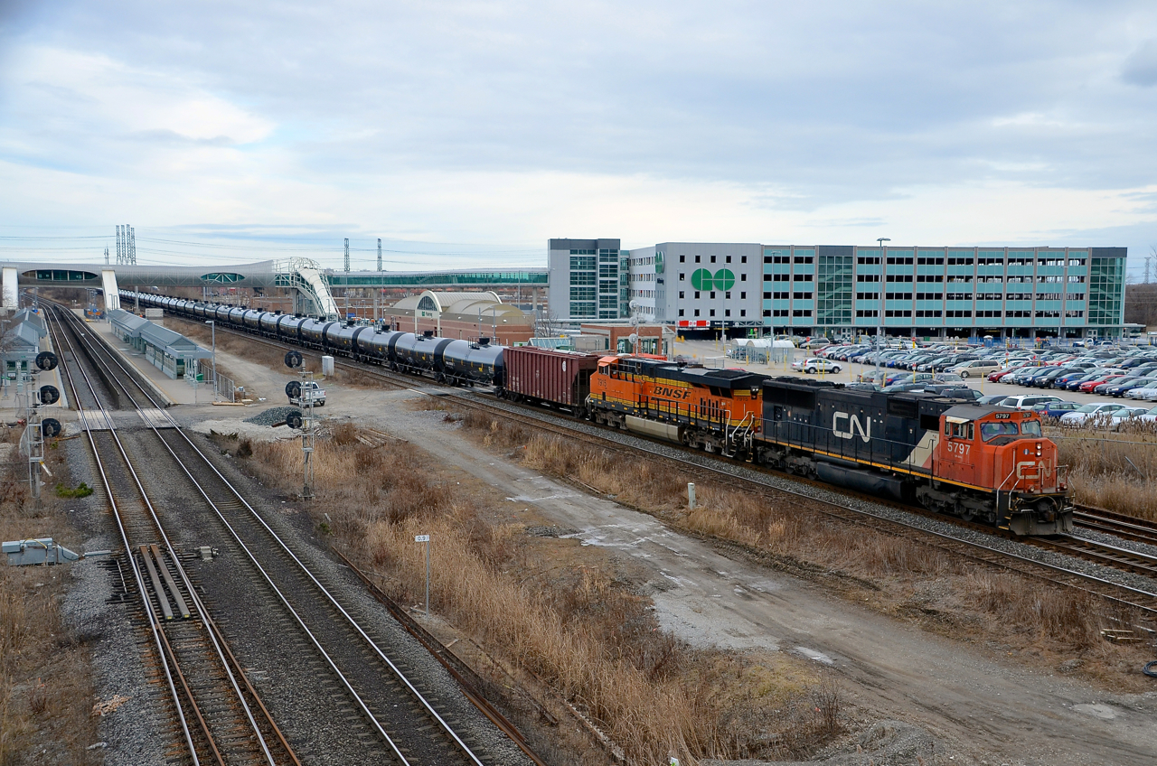 CN 5797 & BNSF 7915 are in charge of CN 711 as it passes the GO parking lot at Pickering. The train (oil empties) is on the Kingston sub but will climb onto the York sub in a few moments. At left is the GO sub.