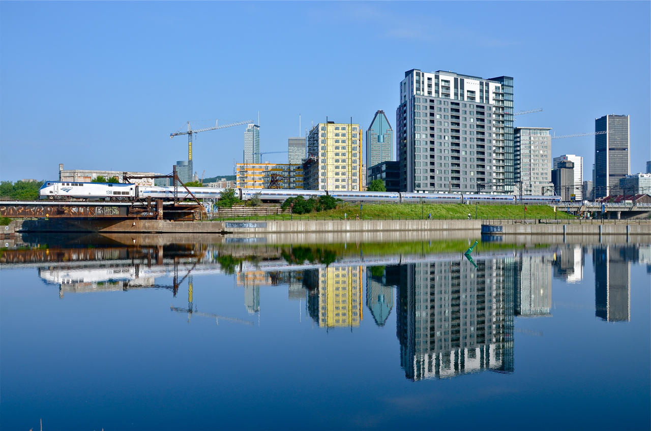 AMTK 138 backs up to Montreal's Central Station with the southbound Adirondack about 75 minutes before departure time on a beautiful morning. In the foreground is the Peel Basin and in the background Montreal's downtown skyline.