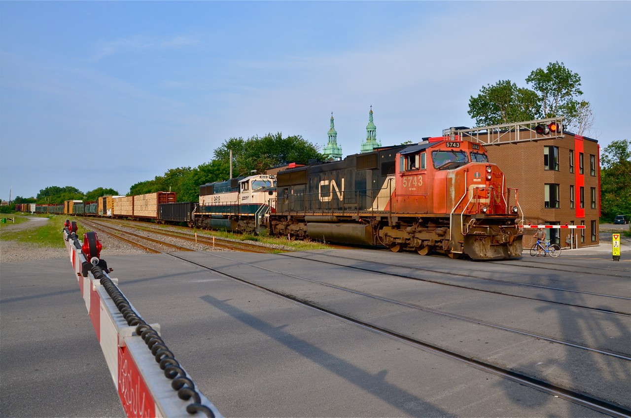 Similar but different. CN 309 crosses De Courcelle street in the St-Henri neighbourhood of Montreal at 6:25 PM with two outwardly identical locomotives (CN 5743 & BNSF 9618) leading and no DPU. CN 5743 is an SD75I built in 1997 and BNSF 9618 is an SD70MAC built for Burlington Northern in 1995. The big internal difference between the two is that the CN unit is DC traction whereas the BNSF unit is AC traction. They make an attractive pair when lashed up together elephant style as they are here.