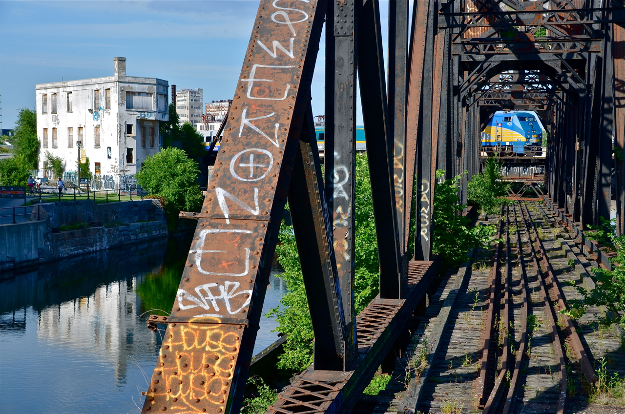 Two CN relics. VIA 39 is deadheading to Central Station with VIA 905 visible through an old CN swing bridge which has been locked in place and out of use for about twenty years. CN freight trains used to use this to access the Port of Montreal but a new route replaced this one. At left is another CN relic: Wellington tower, out of use about a dozen years and rapidly deteriorating. The CN St-Hyacinthe sub in the background sees dozens of AMT, VIA and Amtrak trains every day.