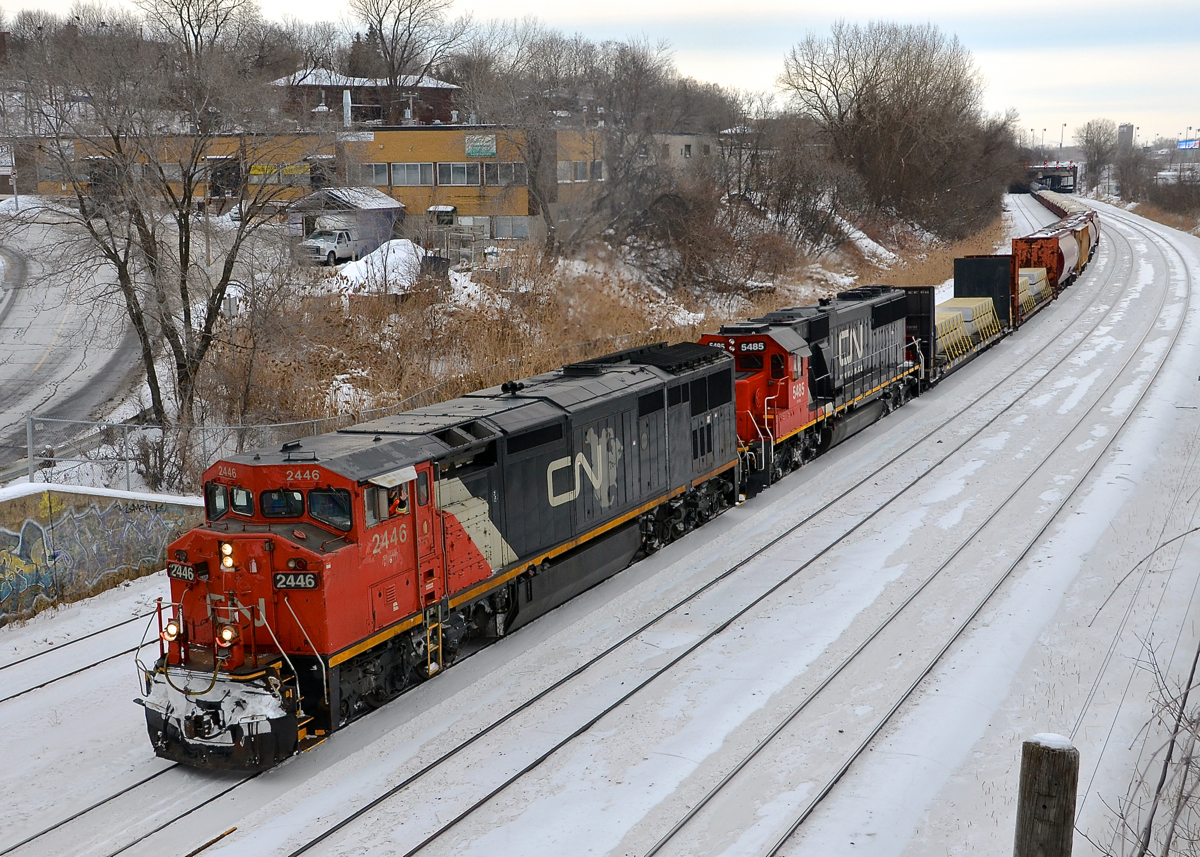 CN X309 is heading west on the freight track of CN's Montreal sub after a crew change at Turcot West with CN 2446 & CN 5485 as power. Fellow railfan and recently qualified CN conductor Nicolas Houde waves from the lead engine on this gray afternoon.