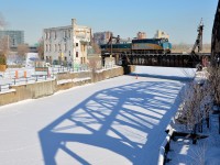 <b>An out of use tower and bridge.</b> VIA 55 bound for Toronto the long way (via Ottawa) is five minutes out of Montreal's Central Station. At left is the out of use Wellington Tower while at right the equally out of use swing bridge casts a shadow on the snow-covered Lachine Canal.