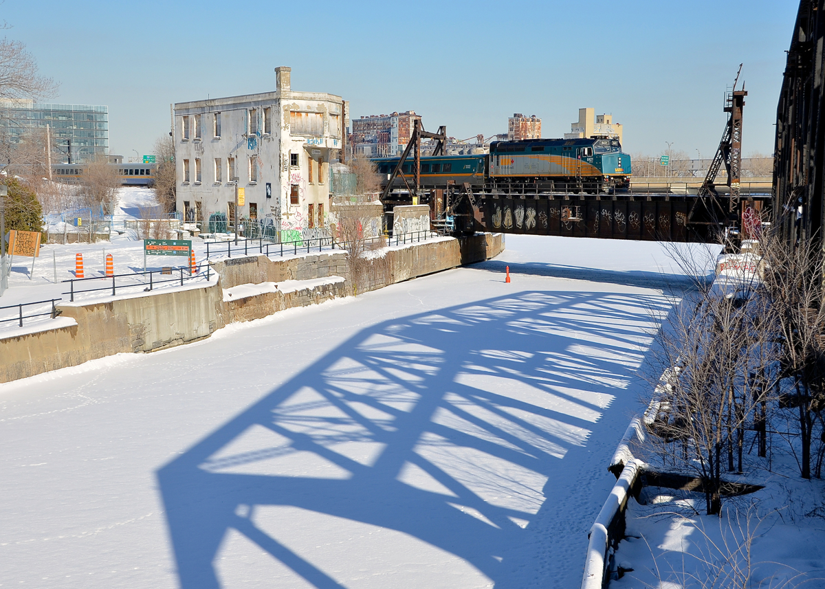 An out of use tower and bridge. VIA 55 bound for Toronto the long way (via Ottawa) is five minutes out of Montreal's Central Station. At left is the out of use Wellington Tower while at right the equally out of use swing bridge casts a shadow on the snow-covered Lachine Canal.