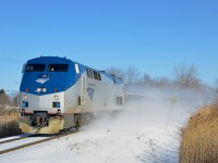 The amfleet cars trailing AMTK 45 on the southbound Adirondack are partially obscured by the snow that it's kicking up as it approaches a grade crossing in Brossard, Qc on a very cold morning.