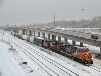 CN X394 for Richmond, Qc heads east on the Montreal Sub with CN 2302 and CN 8959 for power as it paces a car on the parallel highway 20. After a large snowfall overnight it was pouring rain when I got this shot.