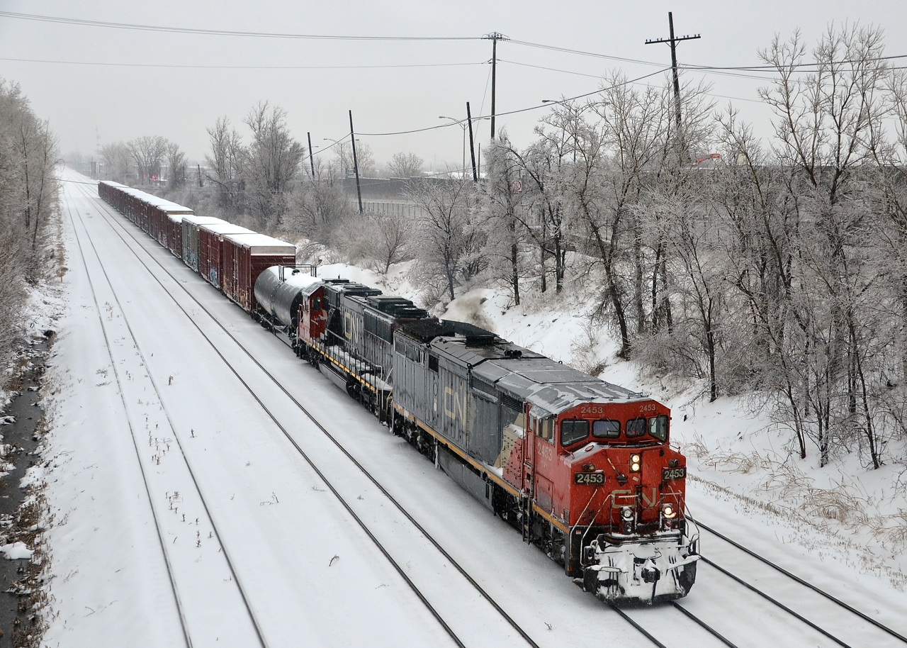 CN 527 heads towards nearby Taschereau Yard with CN 2453 & CN 5445 on a rainy and cold afternoon.