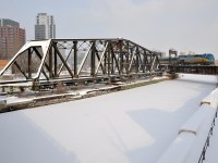 <b>A tale of two bridges.</b> Where the CN St-Hyacinthe sub crosses the Lachine Canal in Montreal (just a bit south of Central Station), there are two bridges. The one at left was a swing bridge that CN freights formerly used to access the Port of Montreal. It has been locked in place and out of use for about two decades. The double-tracked bridge at right (once a lift bridge) is busier than ever, with dozens of movements a day, such as here, with VIA 918 leading VIA 55 towards its eventual destination of Toronto.