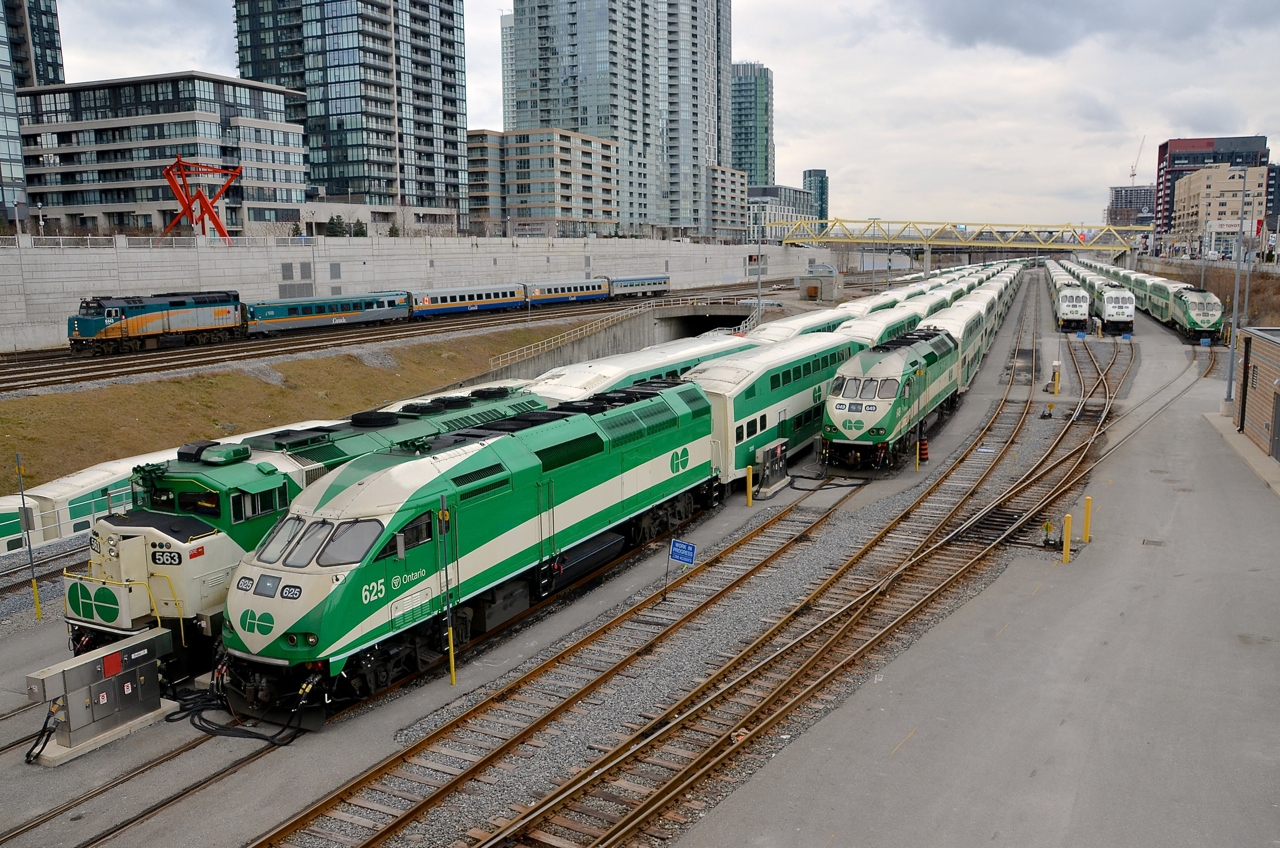 Intruder! All of the trains in this photo are GO Transit trains except for the VIA eastbound led by VIA 6443 which is passing the GO North Bathurst Yard which is filled with 6 trainsets between rush hours. Five are led by MP40PH-3C's while the sixth is led by an F59PH.