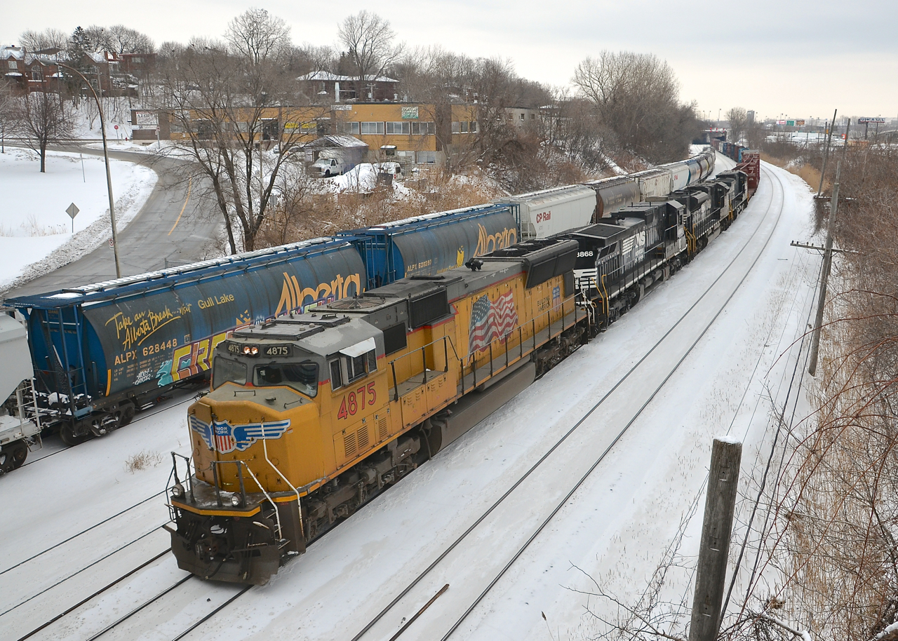 CN 529 is almost finished its trip from Rouses Point as it heads through Montreal West towards its destination of Taschereau Yard a few miles away. It is two days worth of CP 931's (CN picks it up from CP at Rouses Point, NY) and hence has four units rather than the usual two and 476 axles total (much heavier than usual). Power is a UP SD70M leading three NS units (UP 4875, NS 8868, NS 2778 & NS 9518). At left on the transfer track is a long cut of grain cars, perhaps an entire grain train.