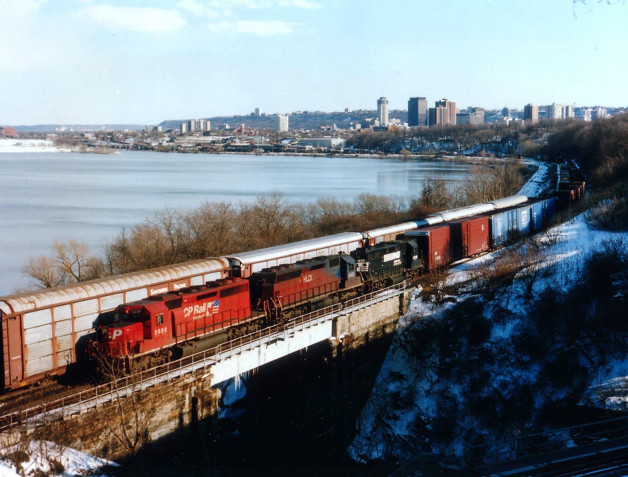 The St. Thomas-Buffalo trains NS 327-328 that once ran daily thru Southern Ontario could be banked on to be early morning trains in the Hamilton area, with 327 westward around dawn, and 328 around 0945, usually just after Amtrak. But there were rare exceptions. In this view we see #327, with CP 5688, HLCX 6400 and NS 2869 on approach to Hamilton Jct at 1640. The sun is getting low to the west. Once #327 cleared onto the Dundas Sub, #328 came thru, the shadow was over the tracks, killing any decent photo. It had a yellow CP, 5430, as sole locomotive up front. Added bonus is a clear air day for Hamilton, not as common then as now.