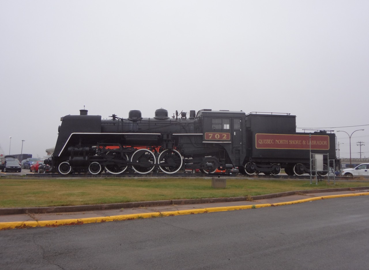 The iron fence and shrubs are cleared away, and QNS&L 702 4-6-2 has been cosmetically freshened up for all to see at the passenger station in Sept-Iles, Quebec on this cool, overcast and drizzly late October morning.