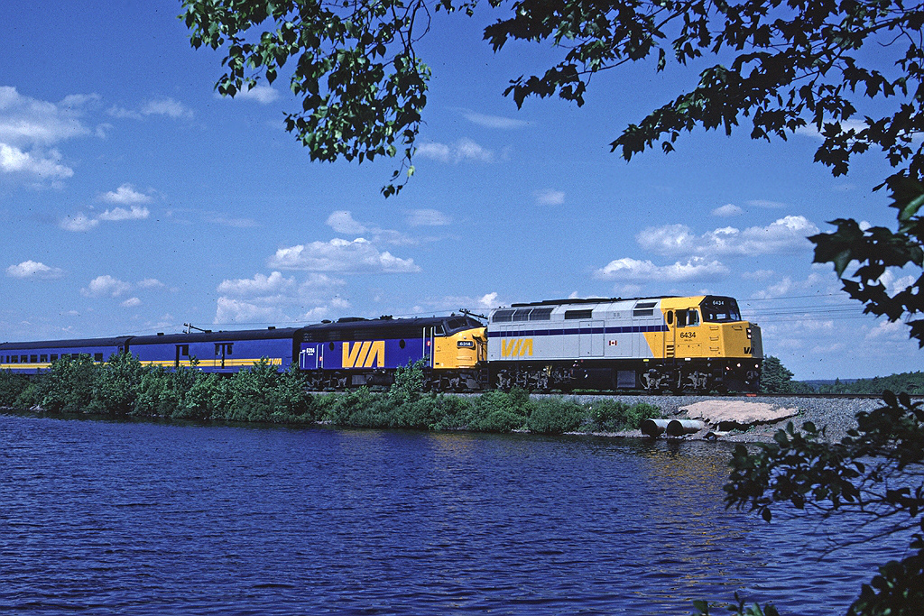 Via # 14, the Ocean, has almost completed its trip from Montreal to Halifax as it crosses Rocky Lake on a causeway. In this transition period between steam and HEP cars the HEP-equipped F40PH is assisted by a steam generator equipped FP9A.