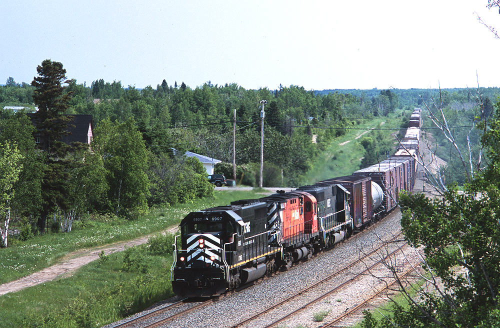 New Brunswick East Coast train #403 on the return leg of its daily turn from Campbellton to Miramachi rolls through Beresford, under Acadia St. At this time chasing #403 required full use of the speed limit on Highway 11 and only resulted in a few shots between Bathurst and Campbellton.