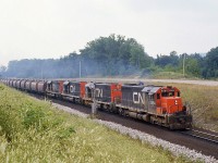 Four matching CN SD40's put their combined 12,000 horsepower to work, splitting the signals at "Mile 30" north of Milton as they motor upgrade with a dedicated unit ore train in Northern Ontario-Hamilton service. <br><br> These "shorty" cylindrical ore hoppers were built by National Steel Car for ore unit train service in three batches: 1967 and 1973/1975. The 1967 cars were 2000 cuft units assigned to Temagami ON and used in unit train service between northern Ontario and Hamilton. The later orders were slightly larger 2300 cuft cars for operation out of Bruce Lake. The hoppers were all designed for automatic loading and unloading, with wheels on the roof hatches that contacted rubbing rails to open and close roof hatches for loading, as well as automated or manual unloading capabilities. CN and Ontario Northland both bought batches and pooled them together for ore train operations (note the ONR's blue & yellow paint and chevrons on the 2nd and 3rd cars).