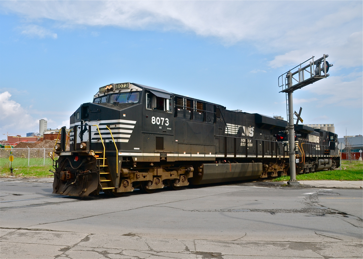 A pair of NS engines (NS 8073 & NS 9533) are returning light from the Port of Montreal after dropping off a grain train. They are crossing Bridge Street, named for the nearby Victoria Bridge which is used by automobiles as well as CN, AMT, VIA Rail and Amtrak trains.